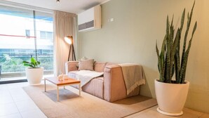 A modern living room with a sofa, a coffee table, a large potted plant, and a view of the outdoors. - HOTEL VIP 46 SSQS (Bagua Grande)