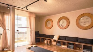 A yoga studio with wooden flooring, a black yoga mat, wooden blocks, a bench, and a window with curtains. - HOTEL VIP 46 SSQS (Bagua Grande)