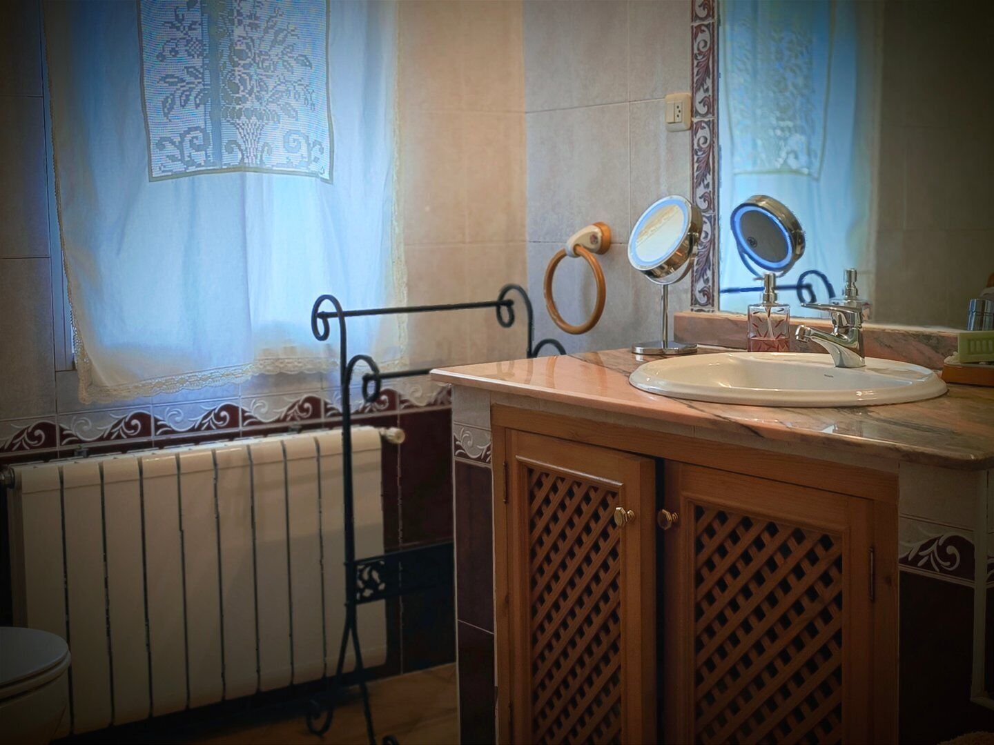 Une salle de bain avec un meuble-lavabo en bois, un évier, un miroir et un porte-serviettes.