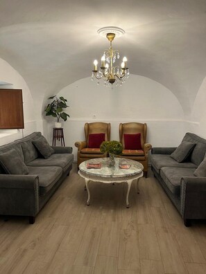 A cozy living room with a chandelier, two armchairs, a sofa, and a small table with a plant. - Casa Filo - Rural house close to Caceres/Trujillo (Plasenzuela)