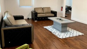 Ein Wohnzimmer mit einer Eckcouch, einem grünen Sessel und einem Couchtisch.
