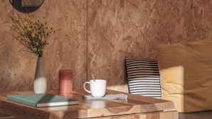 A wooden table with a book, a vase with flowers, a candle, and a mug.