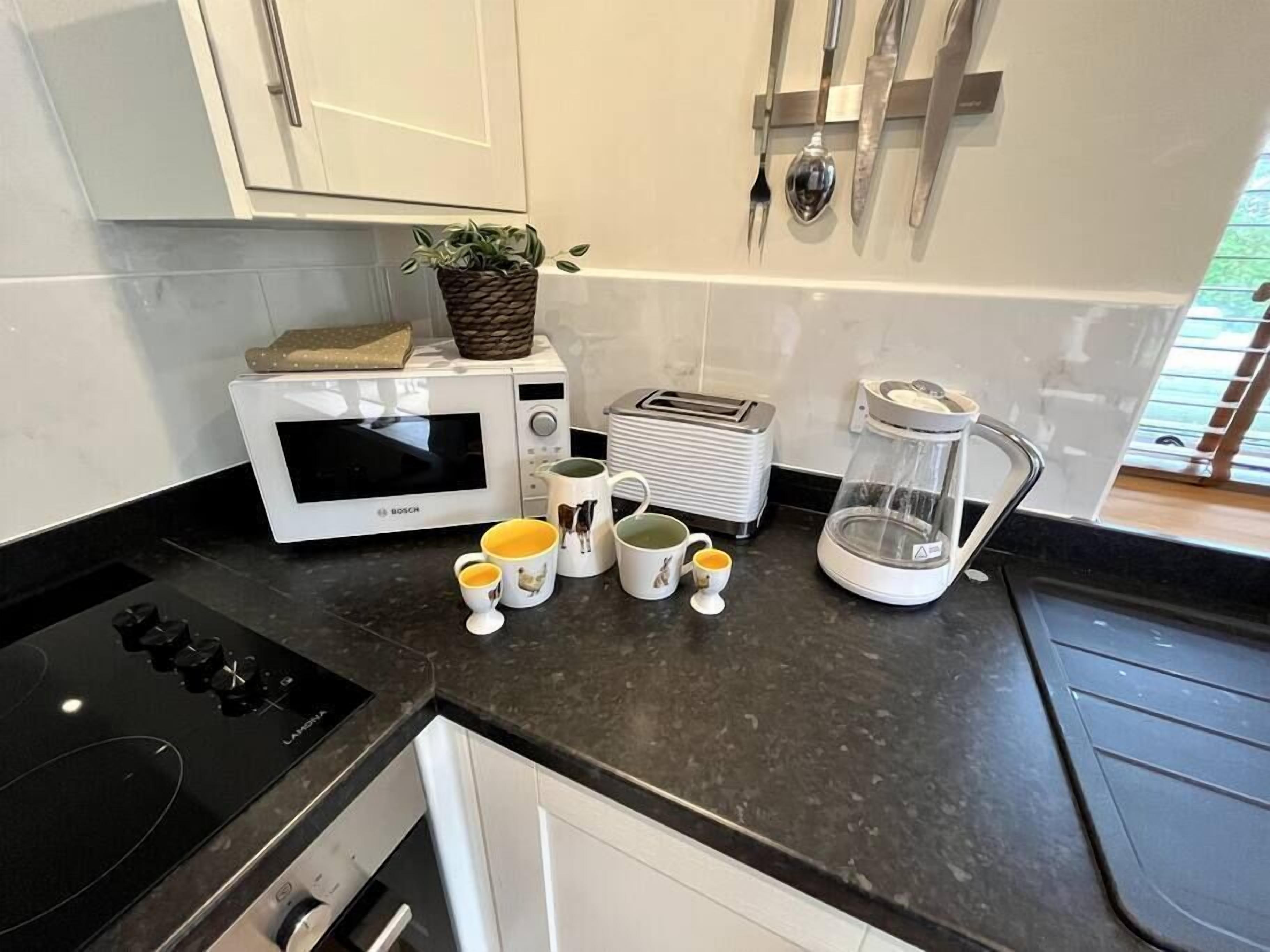 A kitchen with a Bosch microwave, a toaster, a coffee maker, and a sink.