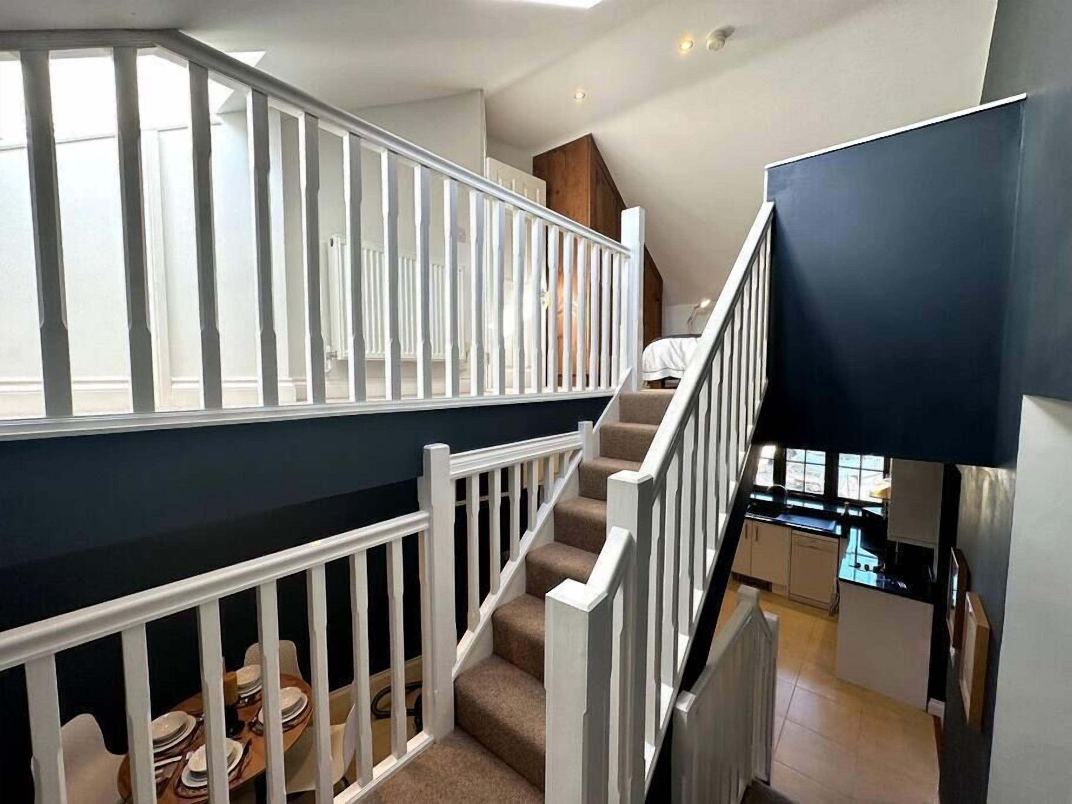Un escalier avec des rampes blanches menant à un deuxième étage.
