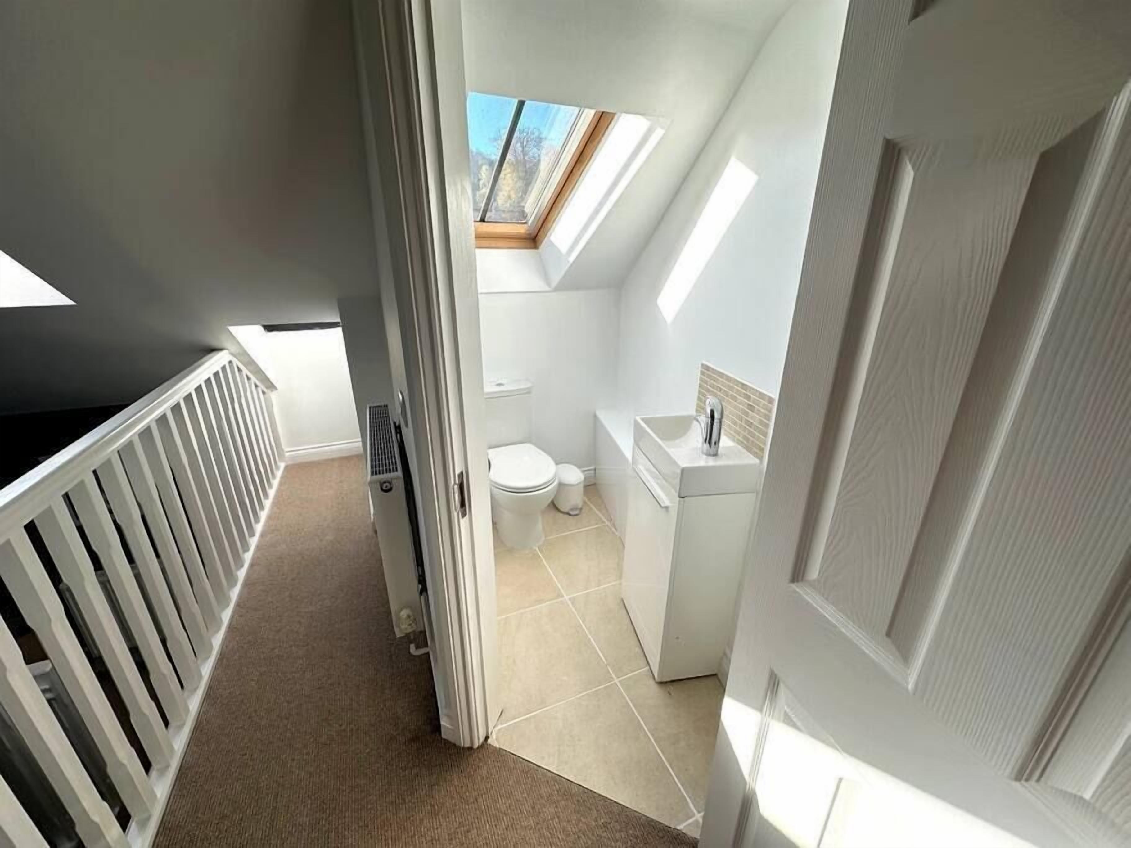 Ein kleines, modernes Badezimmer mit Oberlicht, Toilette und Waschbecken.