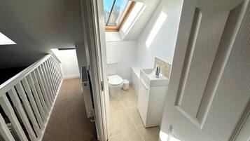 Ein kleines, modernes Badezimmer mit Oberlicht, Toilette und Waschbecken.