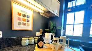 A kitchen counter with a bottle of organic prosecco, a tray with mugs, and a framed poster on the wall. - 2 Car Parking Spaces, Pet Friendly, Central Bakewell In The Peak District (Bakewell)
