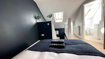 Een moderne slaapkamer met een bed, dakraam en uitzicht op de badkamer.