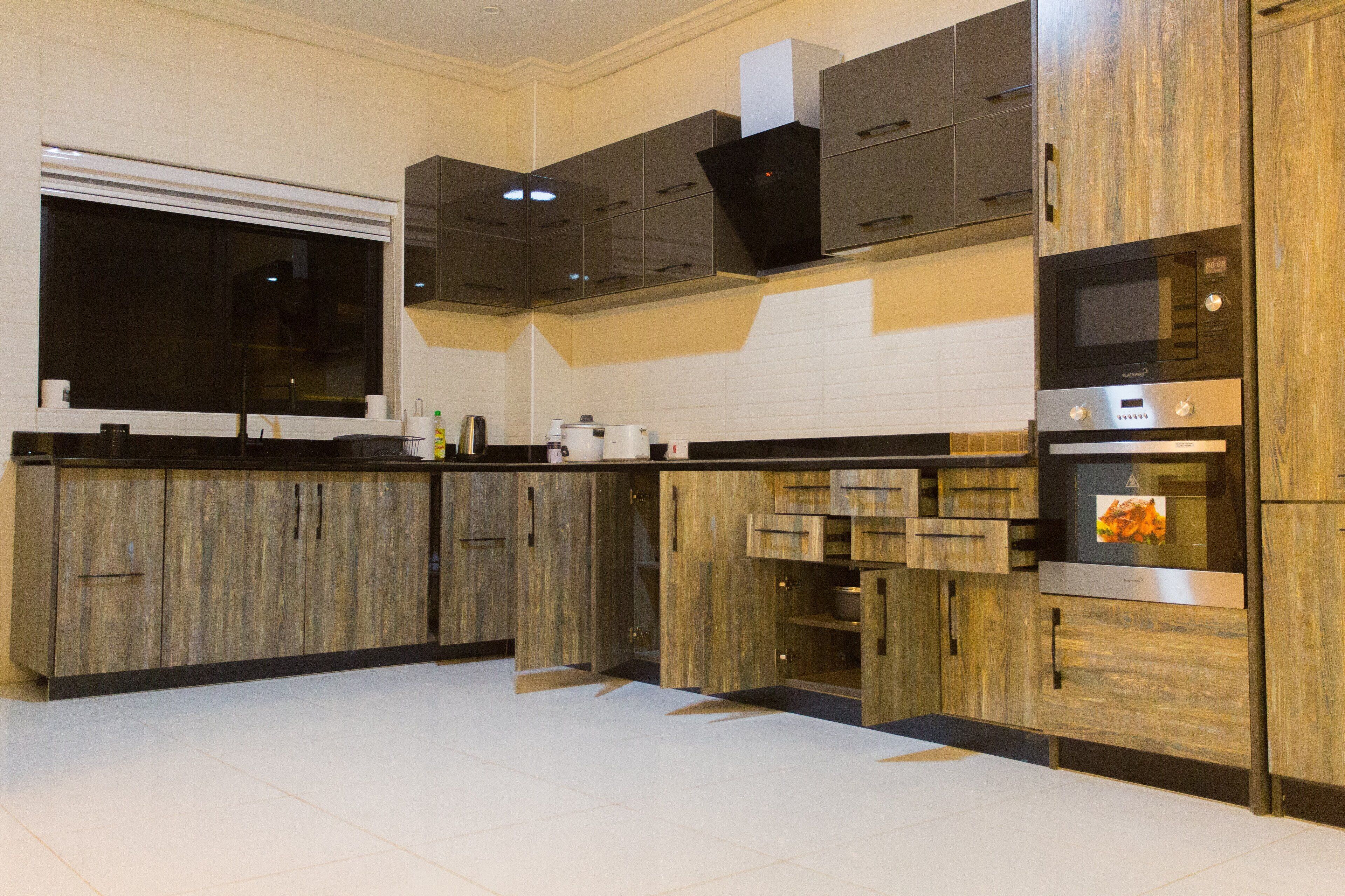 A modern kitchen with wooden cabinets, a black countertop, and stainless steel appliances.