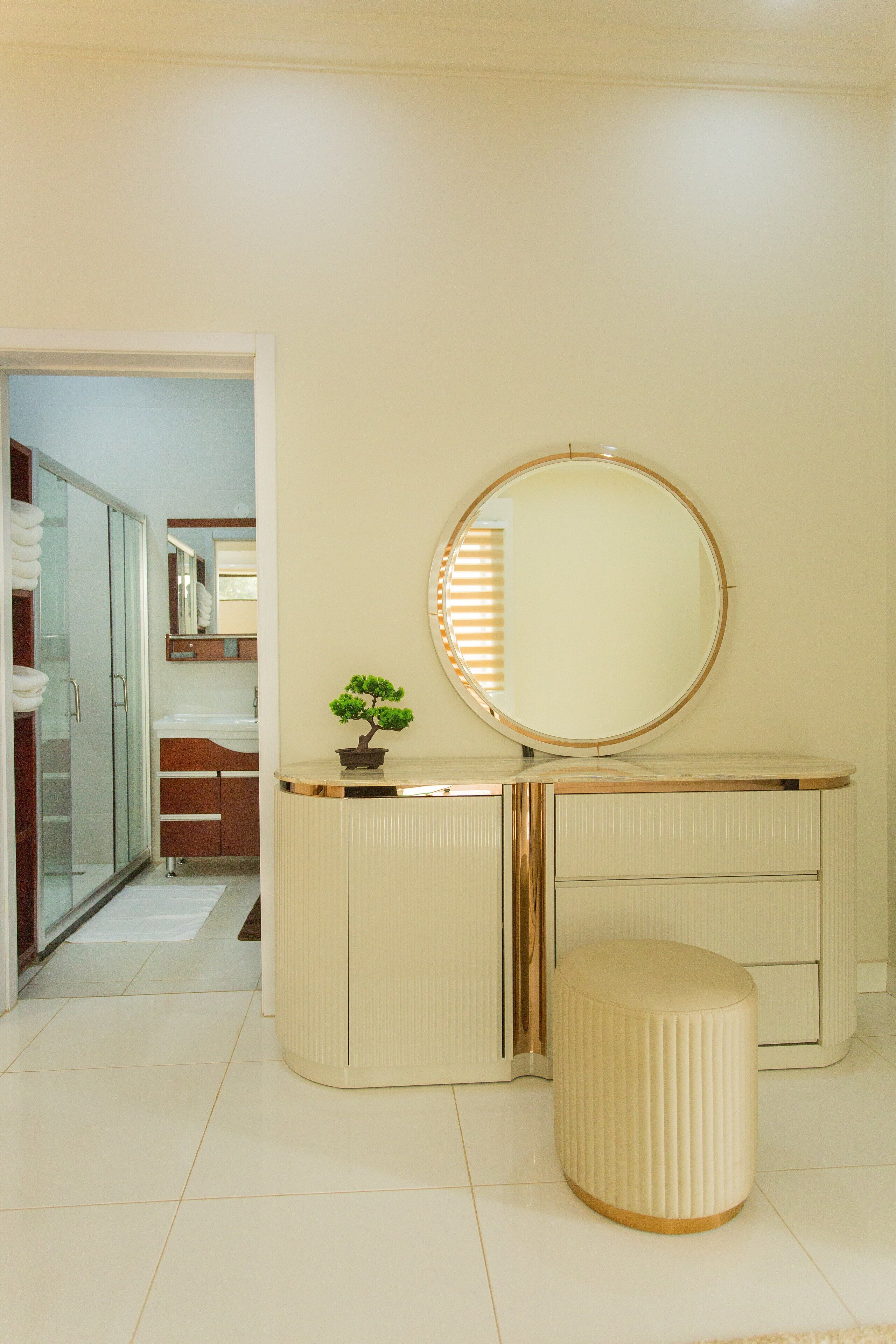Un baño con tocador, espejo redondo y planta en maceta.