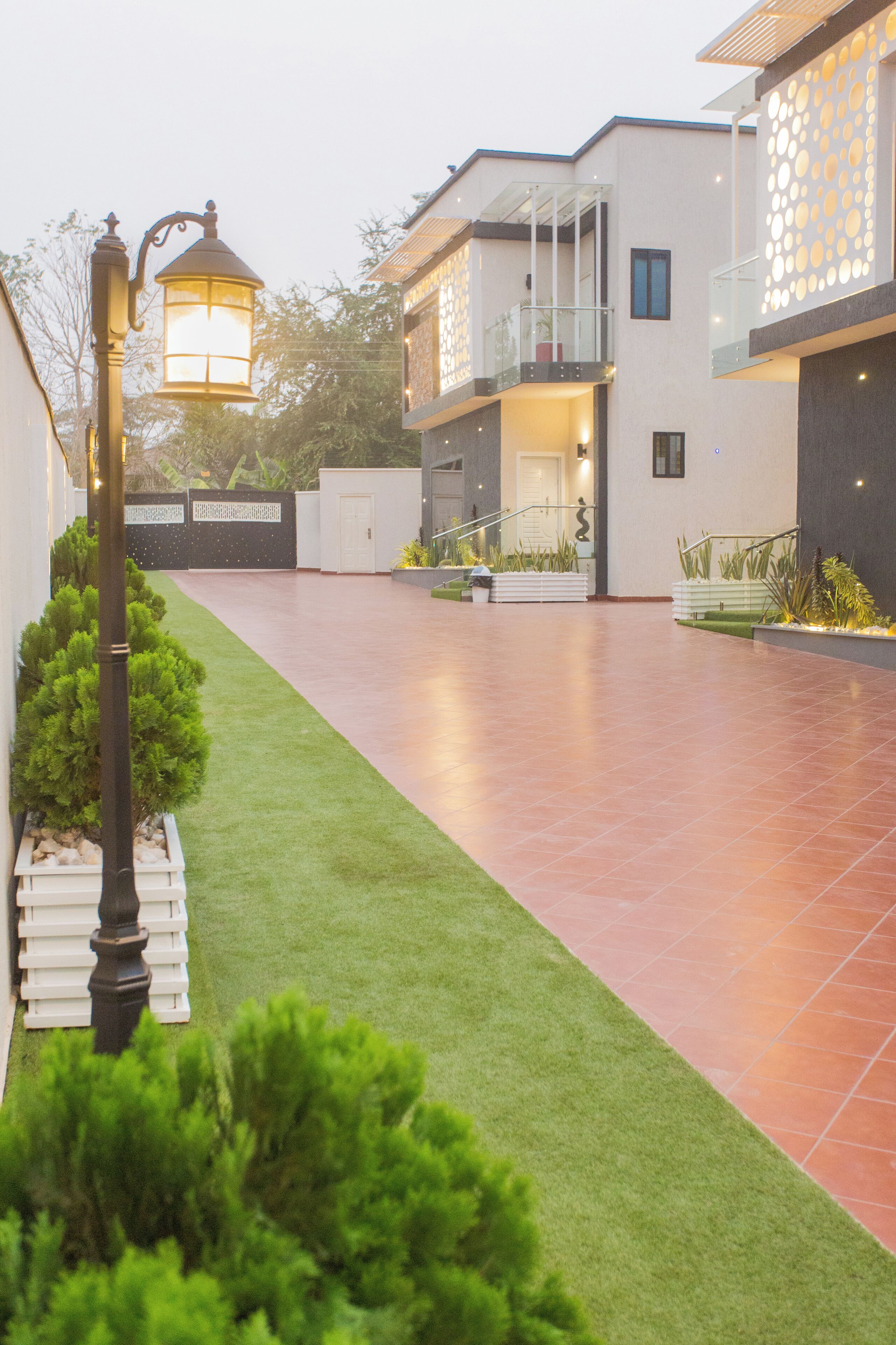 A modern residential building with a spacious patio, a well-maintained lawn, and a decorative street lamp.