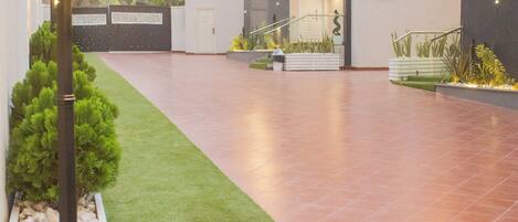 A modern residential building with a spacious patio, a well-maintained lawn, and a decorative street lamp.