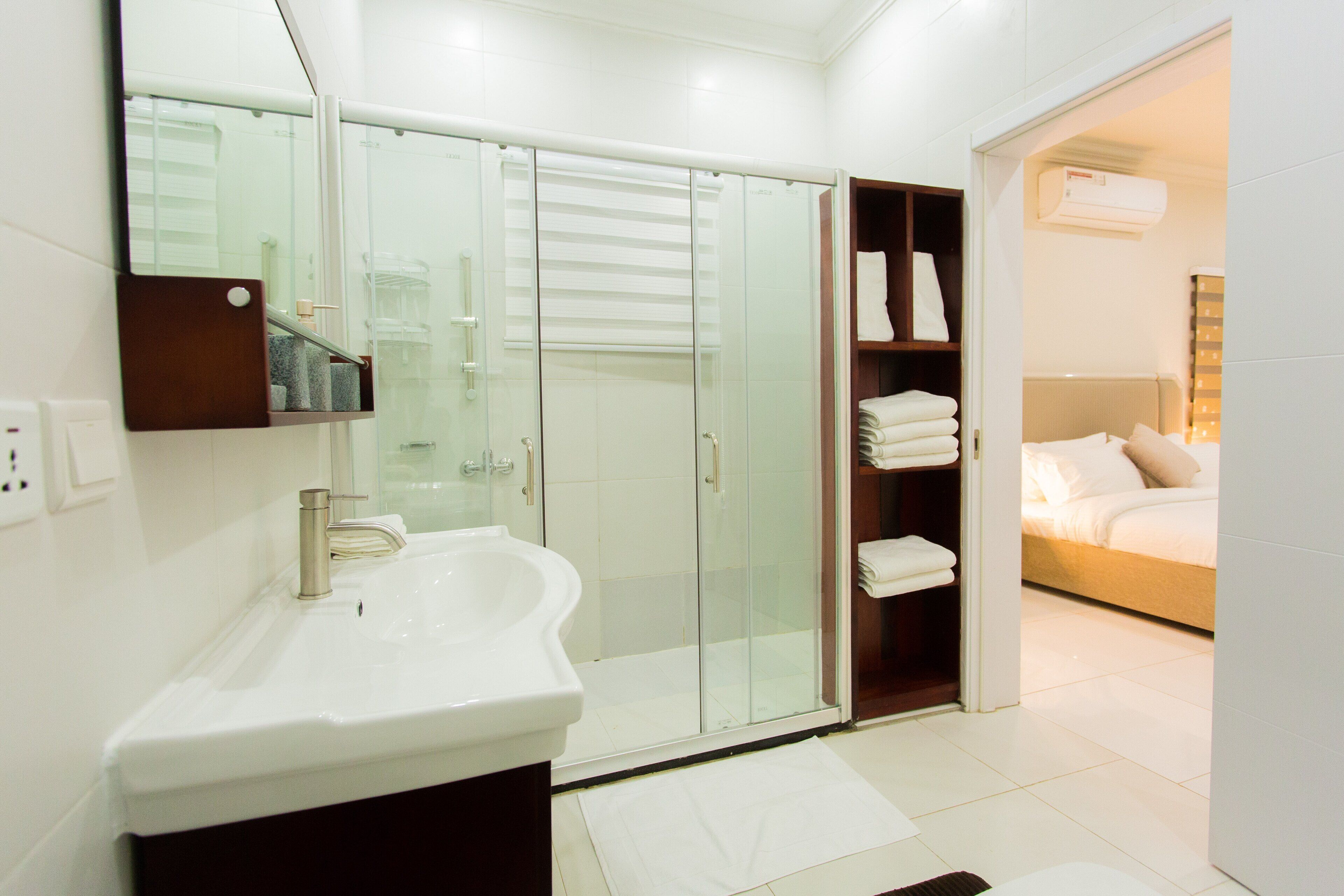 Un baño moderno con un lavamanos grande, cabina de ducha de vidrio y un vestidor con toallas ordenadas.