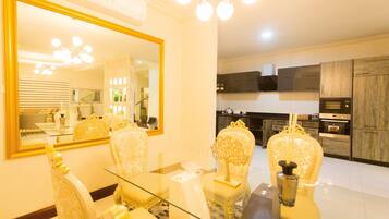 A dining area with a glass table, ornate chairs, and a large mirror.