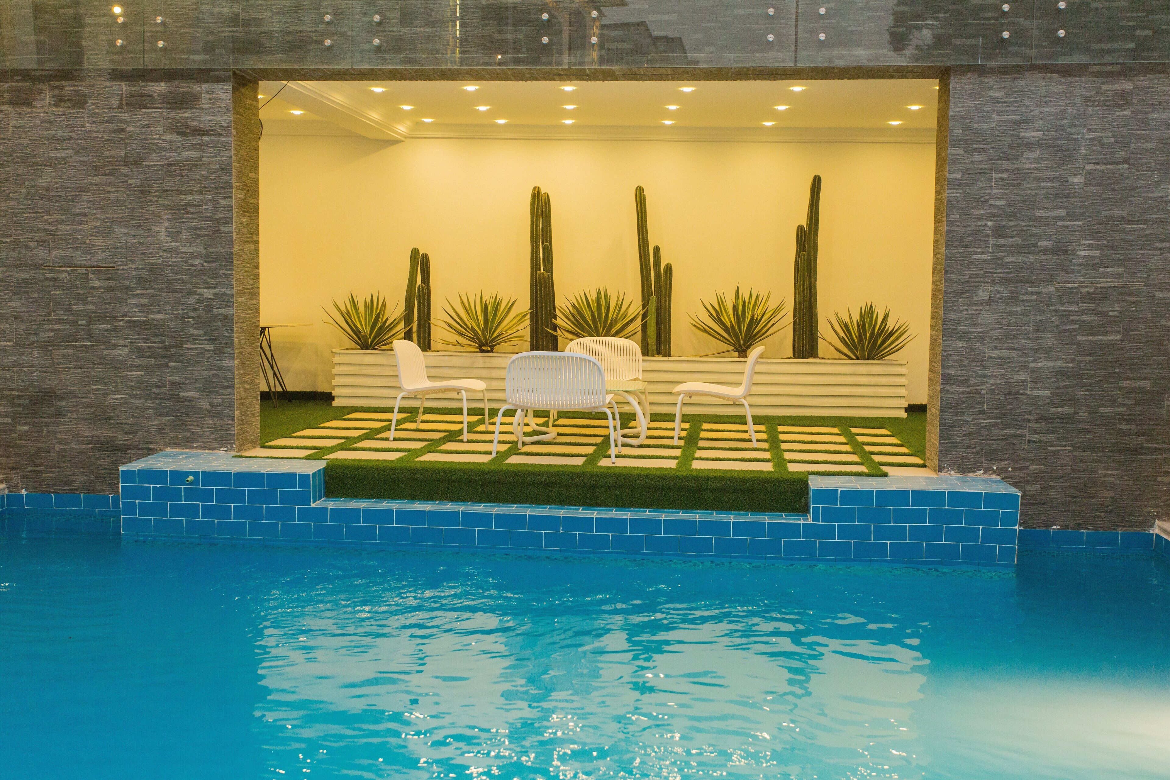 Zona de piscina con mobiliario y cactus.