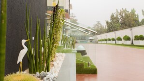 A landscaped area with a white bird sculpture, green plants, and a modern building in the background. - Kumasi Luxury Apartments at The Fairview (Kumasi)