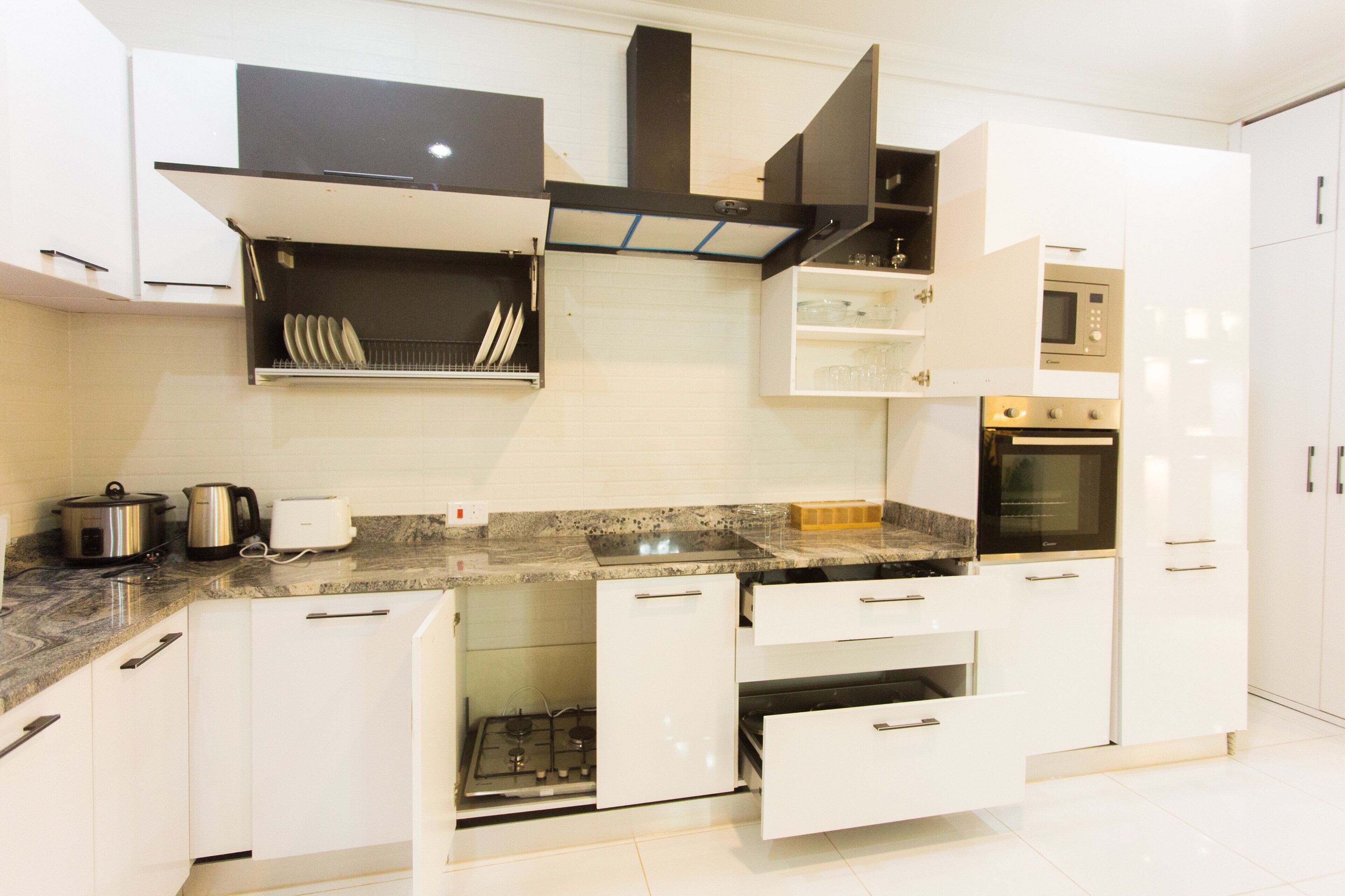 A modern kitchen with white cabinets, a gas stove, a microwave, and a built-in oven.