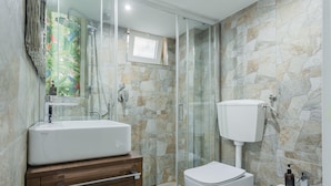 Une salle de bain moderne avec une douche à parois de verre, un lavabo blanc et des toilettes.