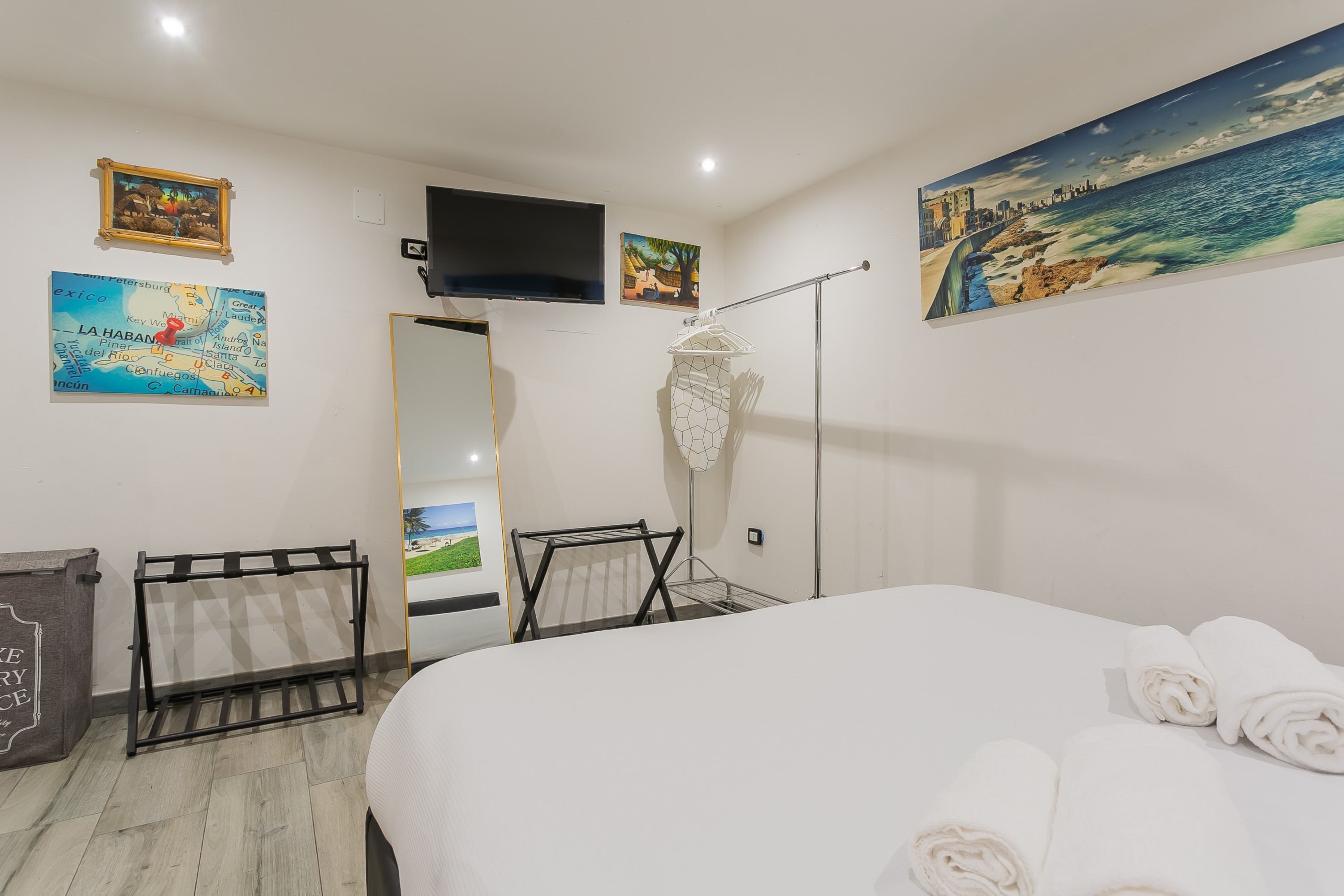 A hotel room with a bed, a TV, a map, and a painting.