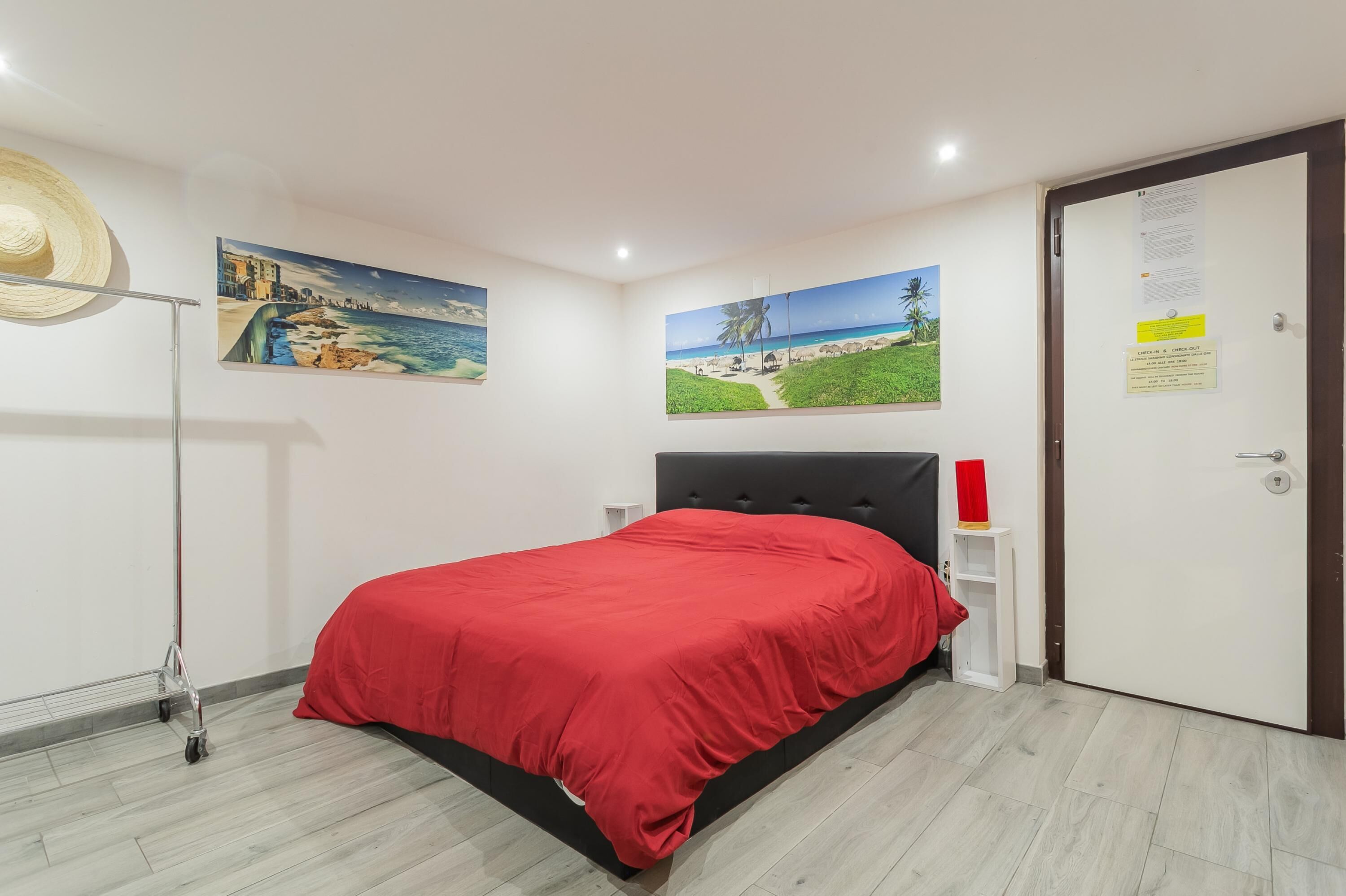 A bedroom with a bed, a door, and two wall-mounted paintings.