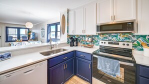 A kitchen with white cabinets, a microwave, a stove, and a dishwasher. - Kill Devil Hills Condo w/ Beach Access On-Site! (Kill Devil Hills)