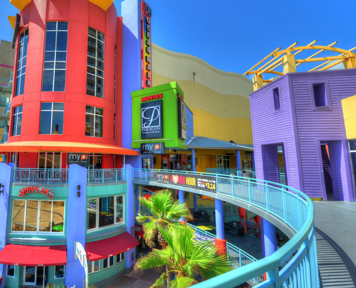A colorful building with a sign for 'Ocean Walk' and 'Movies' on the upper level.