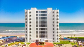 A tall hotel with a central courtyard, multiple balconies, and a view of the beach and ocean. - NEW!Pool!Hot Tub!Oceanfront! Peninsula #303 (Daytona Beach)
