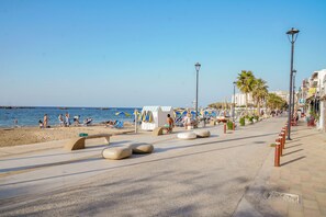 A beachside promenade with a clear sky, palm trees, and beach umbrellas. - Aeri Home - At Nea Chora beach w. Parking included (Chania)