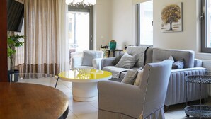 A living room with a sofa, armchairs, a coffee table, and a TV. - Aeri Home - At Nea Chora beach w. Parking included (Chania)