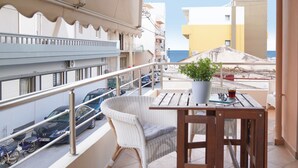 A balcony with a wicker chair, a wooden table, and a potted plant. - Aeri Home - At Nea Chora beach w. Parking included (Chania)