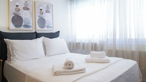 A neatly made bed with white linens, a dark headboard, and two framed artworks above it. - Aeri Home - At Nea Chora beach w. Parking included (Chania)