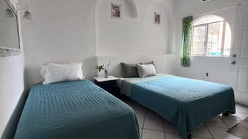 Una habitación con dos camas, ventilador de techo, aire acondicionado y una ventana con cortina.