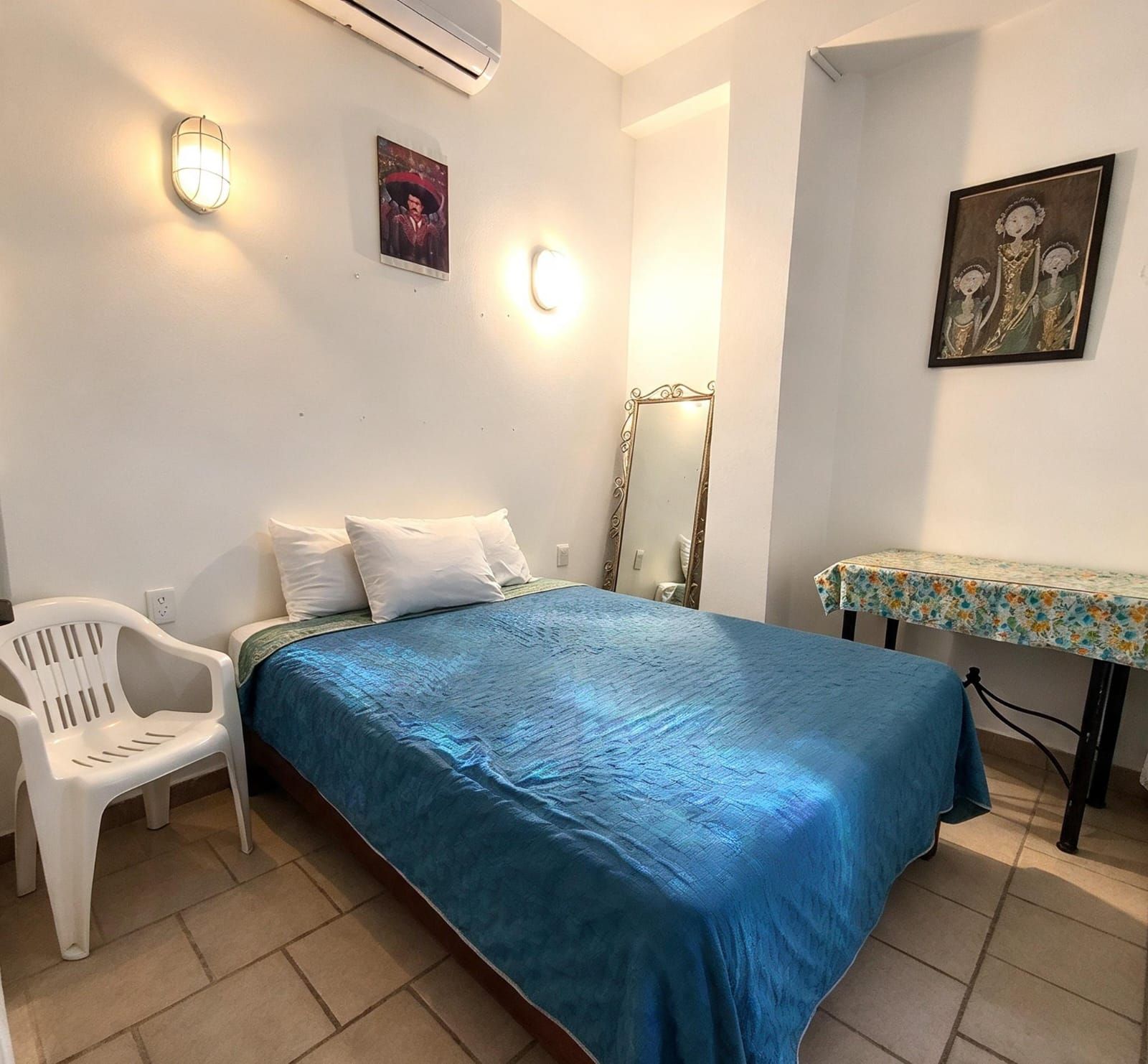 Un dormitorio con cama, una silla, una mesa y un espejo.