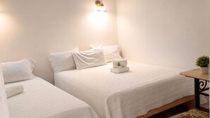 Une chambre d’hôtel avec deux lits, une petite table ornée d’une plante et un luminaire fixé au mur.