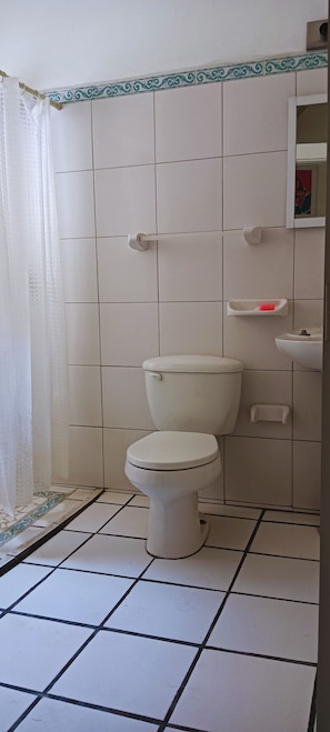 Une salle de bain avec des toilettes, un lavabo et un miroir.