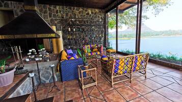 A cozy outdoor seating area with stone walls, a fireplace, and a view of a lake.