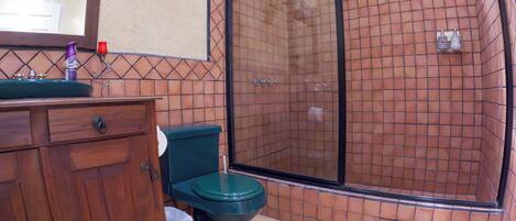 Een badkamer met douche, toilet en wastafel.