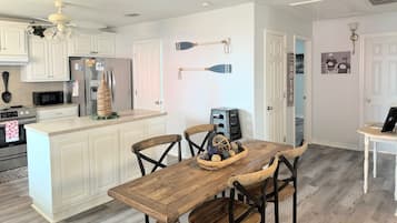 A kitchen with white cabinetry, a wooden dining table, and a ceiling fan.