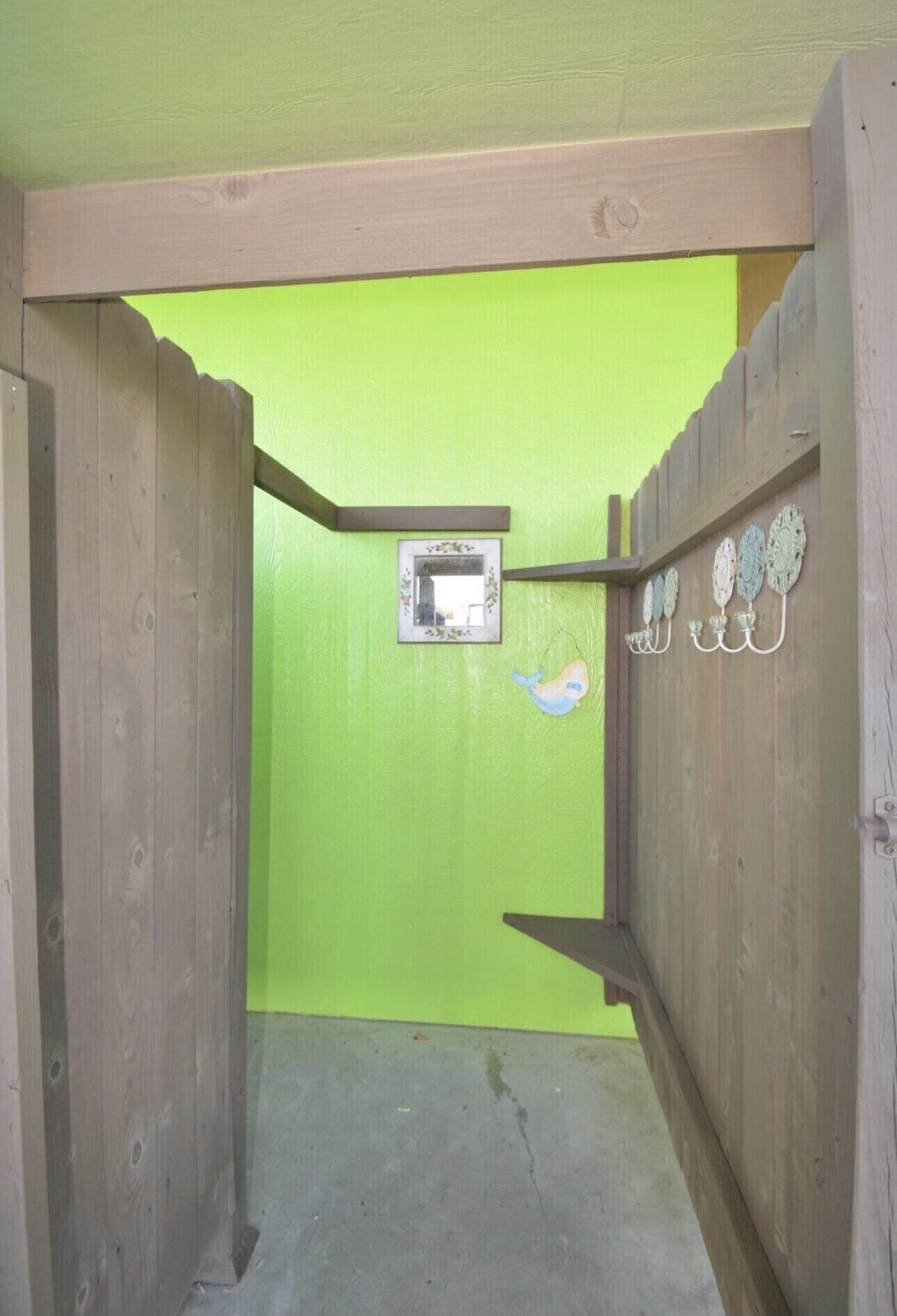 Een smalle houten gang met een groene muur en een klein raam.