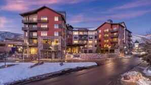 A multi-story hotel with a stone facade and multiple balconies, featuring a central courtyard and a view of a snow-covered landscape. - Presidential Unit at a World Class Ski Resort
 (Avon)
