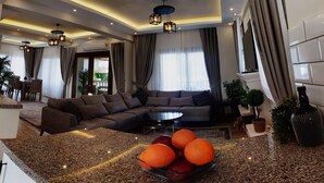 Een moderne woonkamer met een hoekbank, een bijzettafeltje en een schaal fruit.