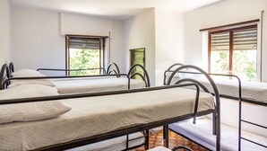 A dormitory room with four bunk beds, each with a metal frame and white bedding. There are windows with wooden shutters, and a green painting on the wall. - RIFUGIO TAGLIACOZZO (Tagliacozzo)