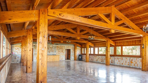 A spacious hall with wooden beams, stone walls, and large windows. - RIFUGIO TAGLIACOZZO (Tagliacozzo)