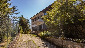 A pathway leading to a two-story building with a stone wall and a metal fence on one side. - RIFUGIO TAGLIACOZZO (Tagliacozzo)