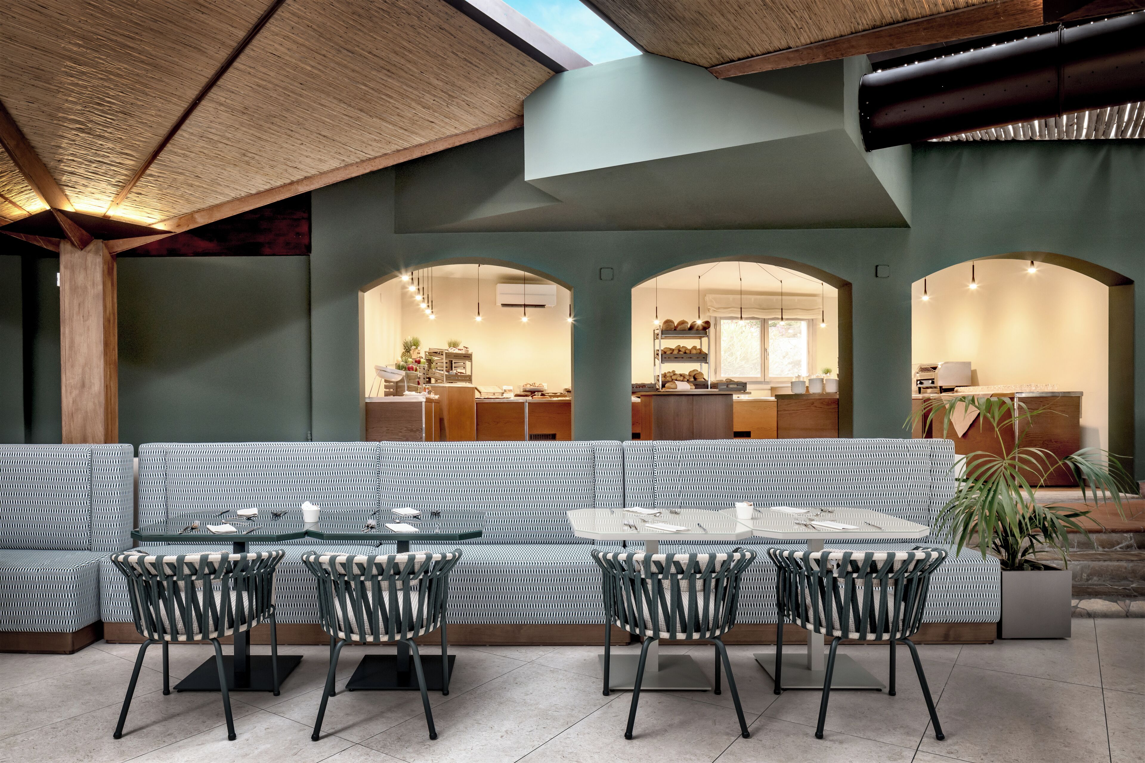 Een modern interieur met een lange bank, ronde tafels en stoelen.