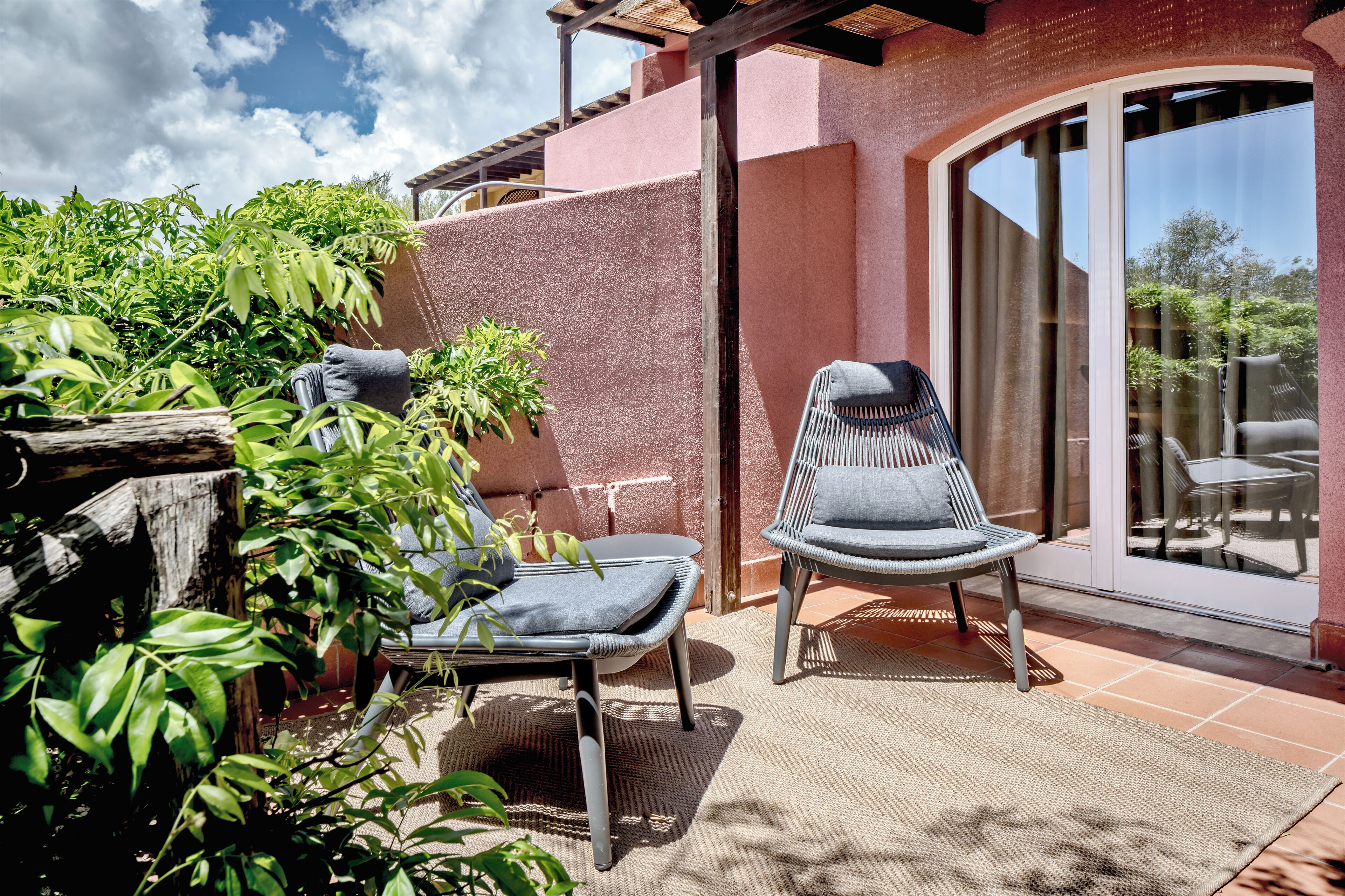 Un patio con dos sillas, una mesa y una planta en maceta.