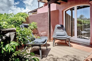 A patio area with two chairs, a table, and a potted plant. - Veridia Resort Sardinia, A Member Of Radisson Individuals (Domus de Maria)