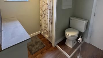 Ein kleines Badezimmer mit Toilette, einer Duschkabine und einem Fenster.