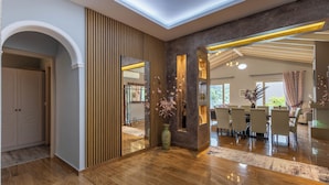 A modern interior with a wooden floor, a dining area with a table and chairs, and a large mirror. - Villa Jewel in Corfu (Kontokali)