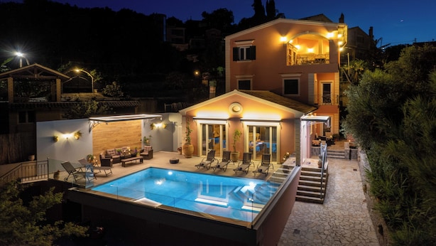 A two-story building with a swimming pool, outdoor seating, and a staircase leading to the upper floor. - Villa Jewel in Corfu (Kontokali)